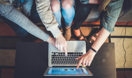 three person pointing the silver laptop computer