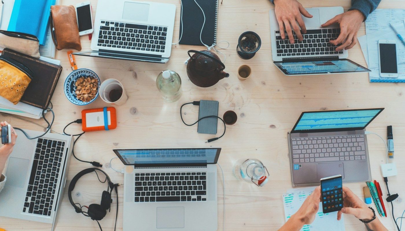 people sitting down near table with assorted laptop computers